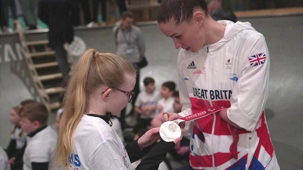 Paralympian Beth Munro shows her silver medal to a school student.