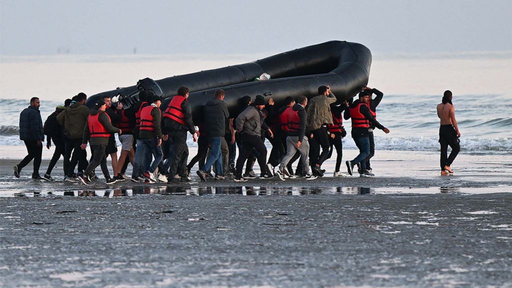 Migrants carry a boat towards the water before they attempt to cross the Channel illegally to Britain, July 2022