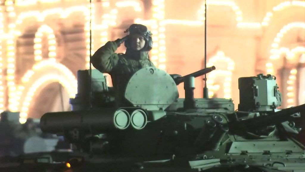 A soldier saluting from the top of a tank