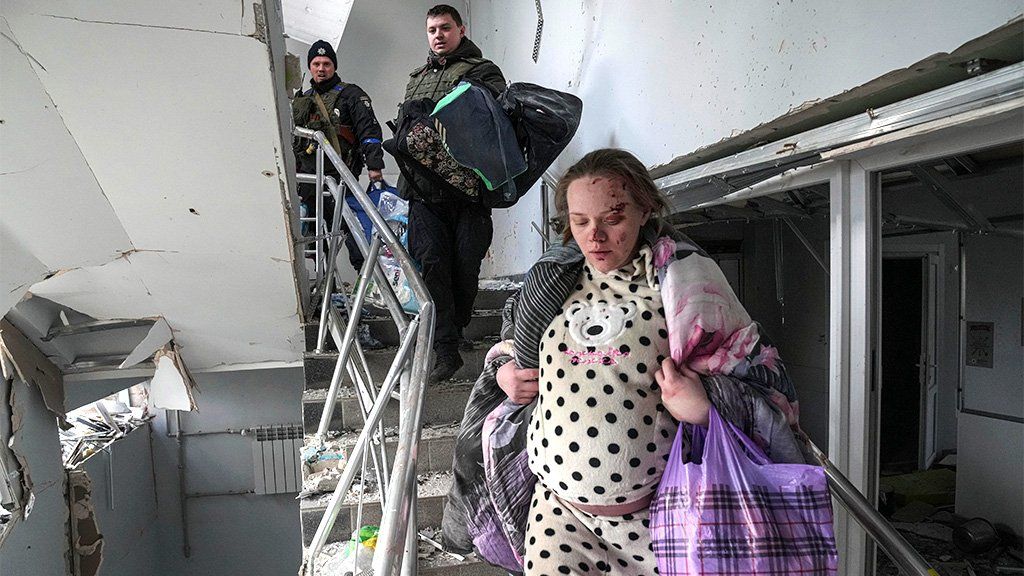 An injured pregnant woman walks downstairs in a maternity hospital damaged by shelling in Mariupol