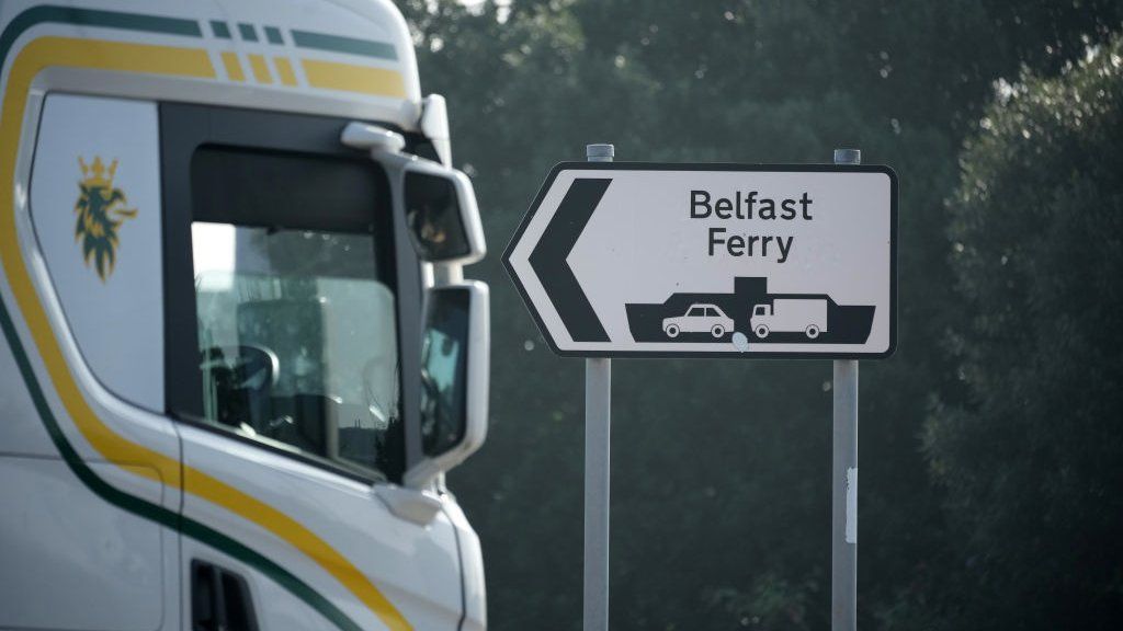 A lorry cab sits beside a sign reading "Belfast Ferry"