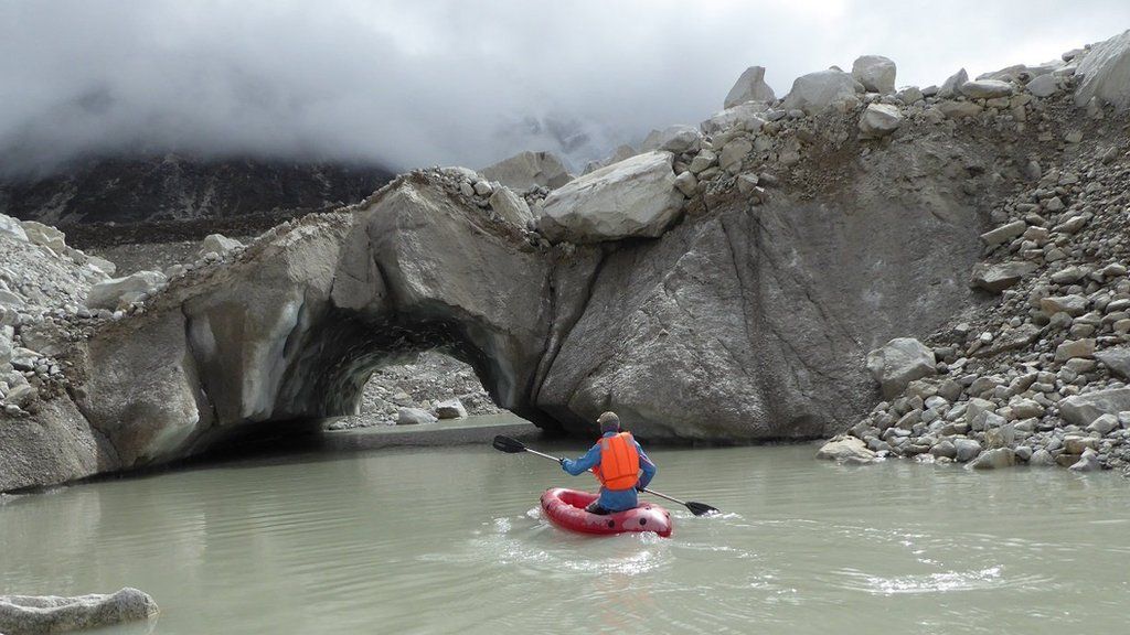 Scientist in a kayak assessing the melting glacier