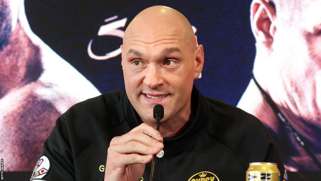 Tyson Fury speaks on the microphone at a news conference