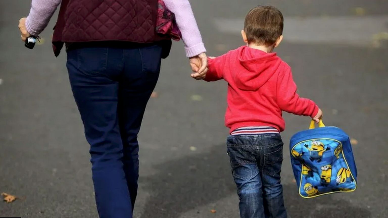 Woman and child walking down the street hand in hand