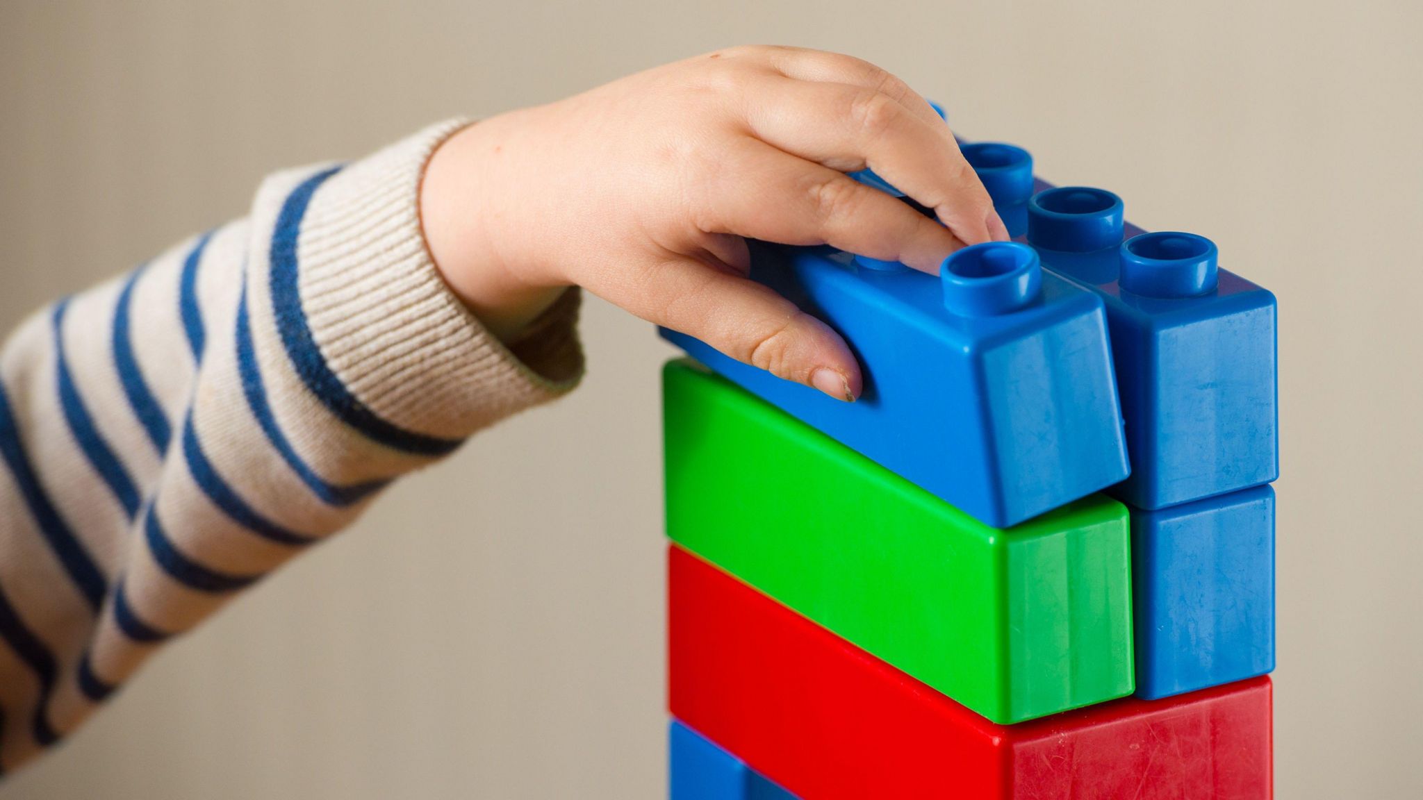 A pre-school age child playing with plastic building blocks