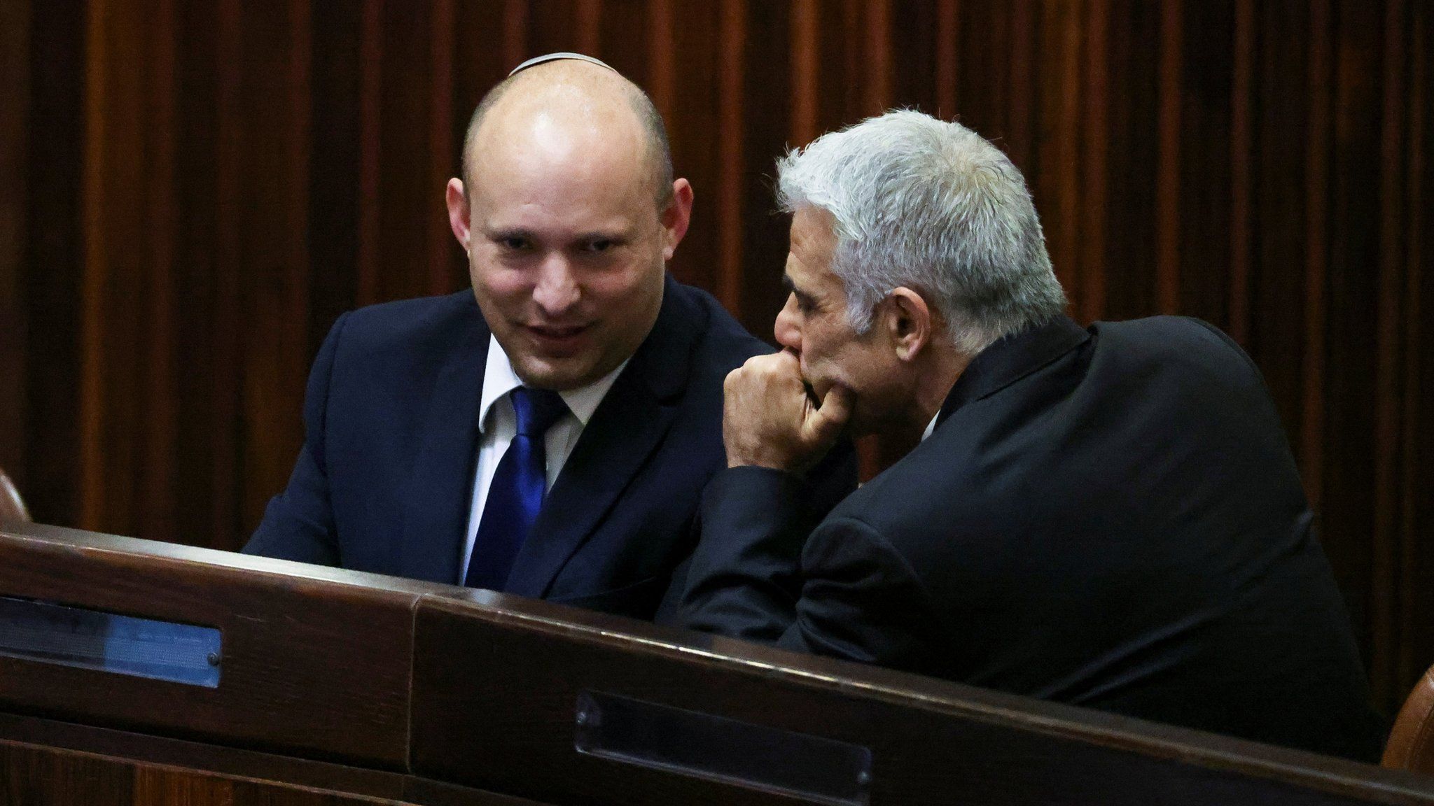 Israeli politicians Naftali Bennett (L) and Yair Lapid (R) talk during a parliamentary session in Jerusalem (2 June 2021)