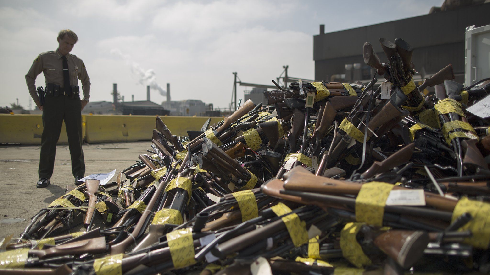 A Los Angeles County Sheriffs deputy looks at a pile of guns on July 6, 2015 in Rancho Cucamonga, California.