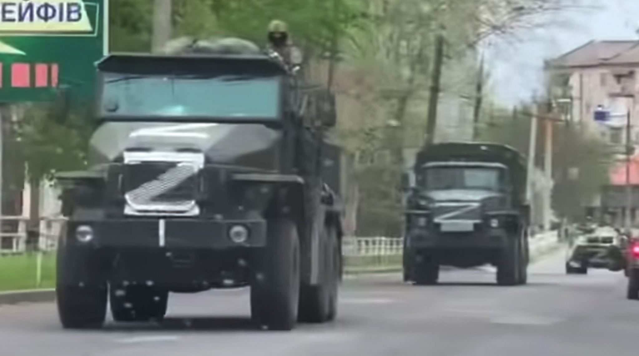 Large Russian Trucks with white Z painted on them drive down a street