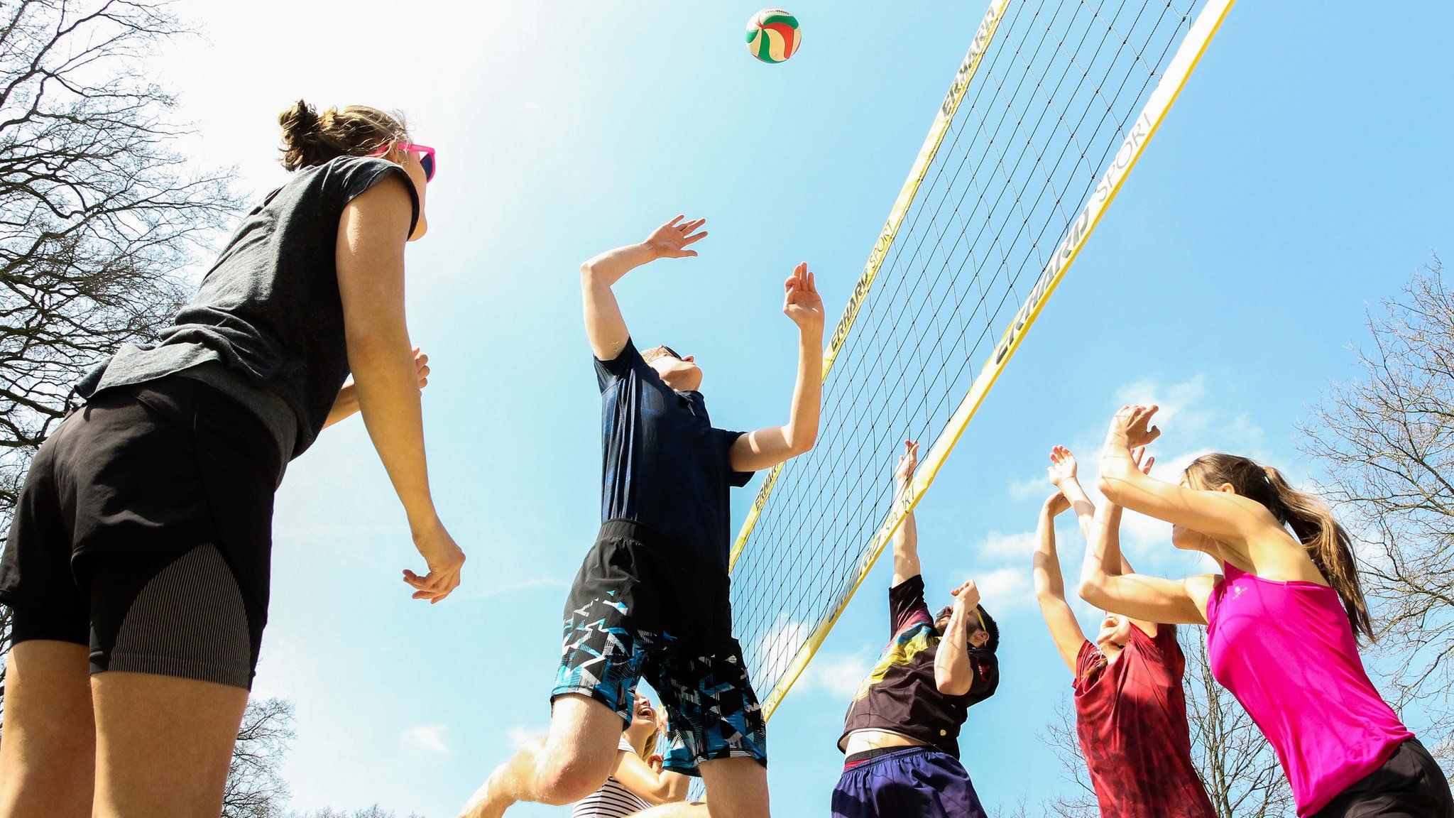 Friends playing volleyball outside in the sun