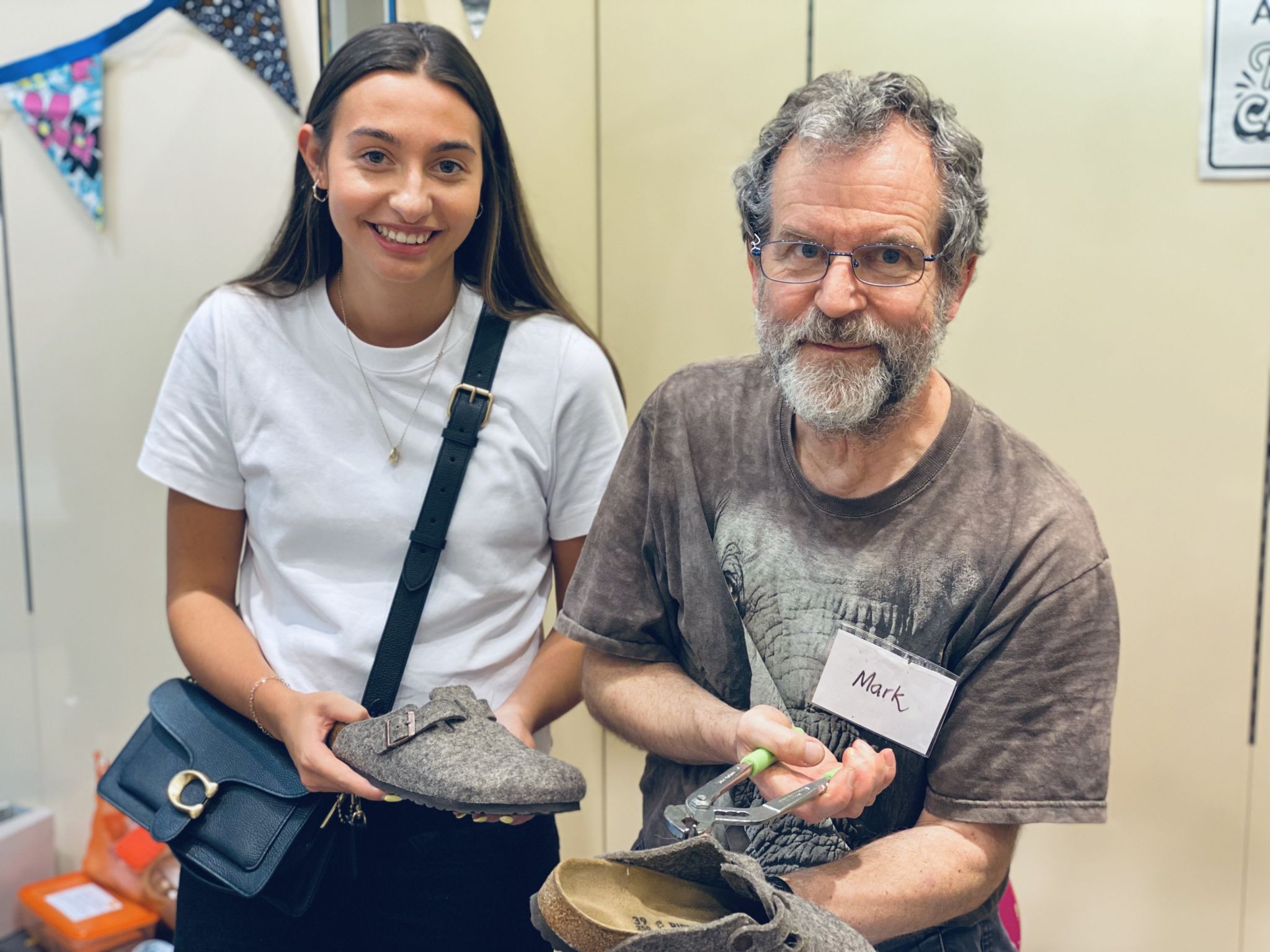 Woman standing with her fixed felt shoes standing next to a man with a tool
