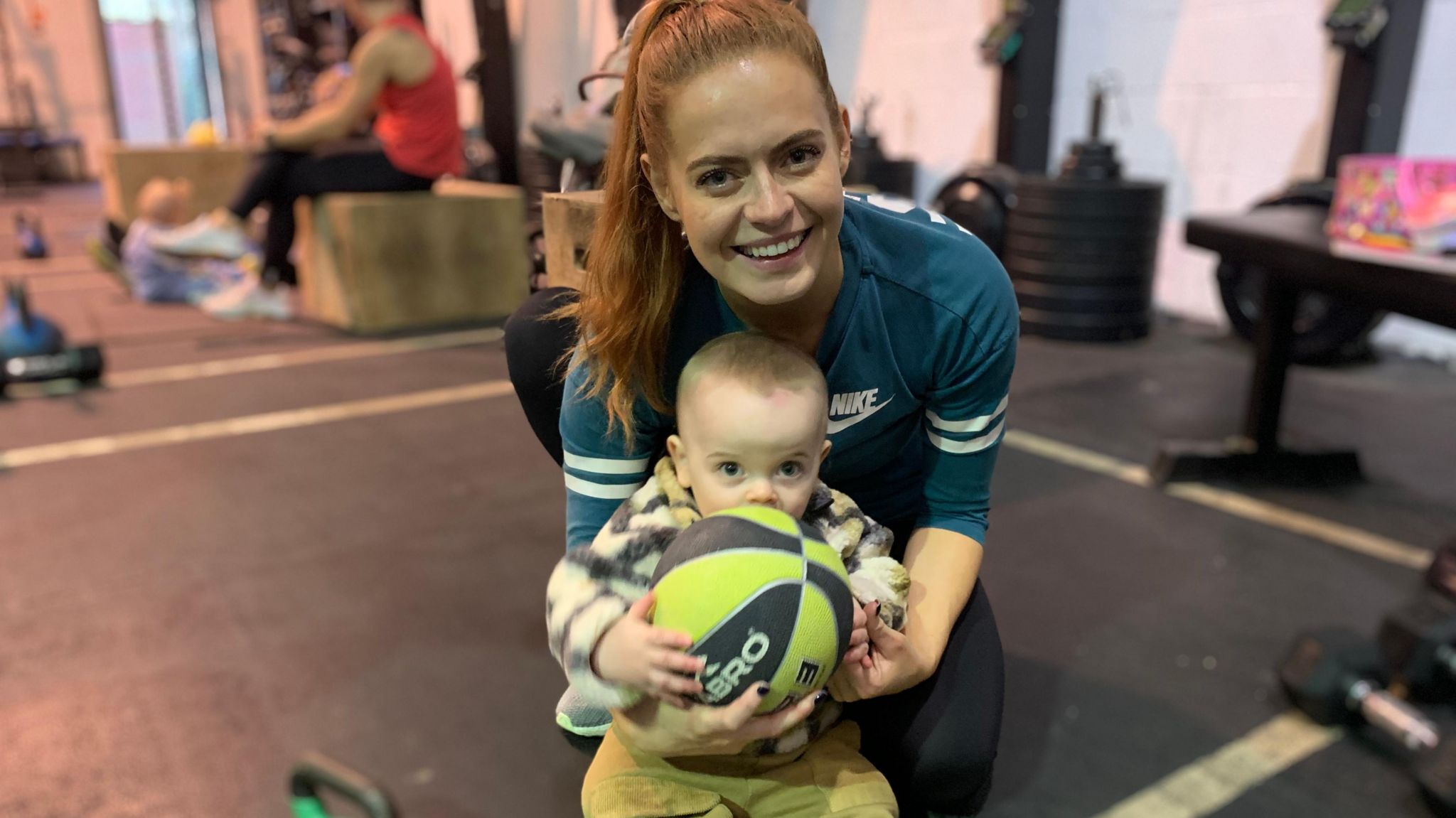 Sophie Evans and baby Jack lifting a ball in the gym