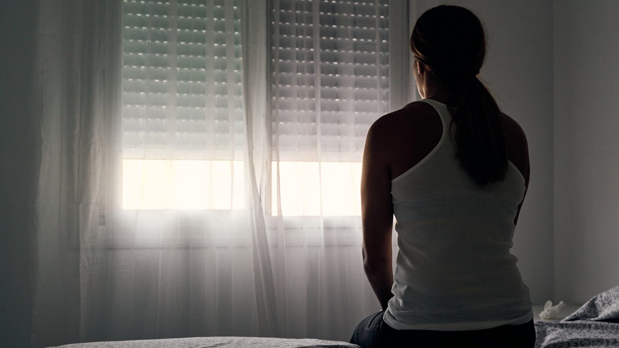 woman sits alone opposite window