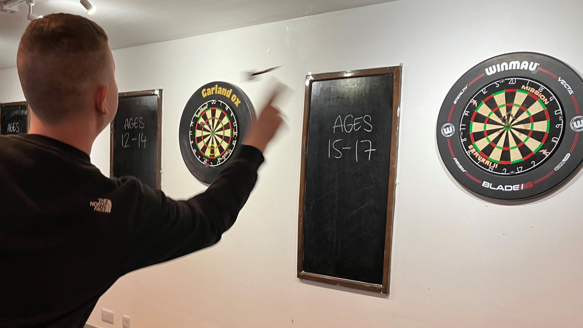 Teenager throwing a dart at dartboard 