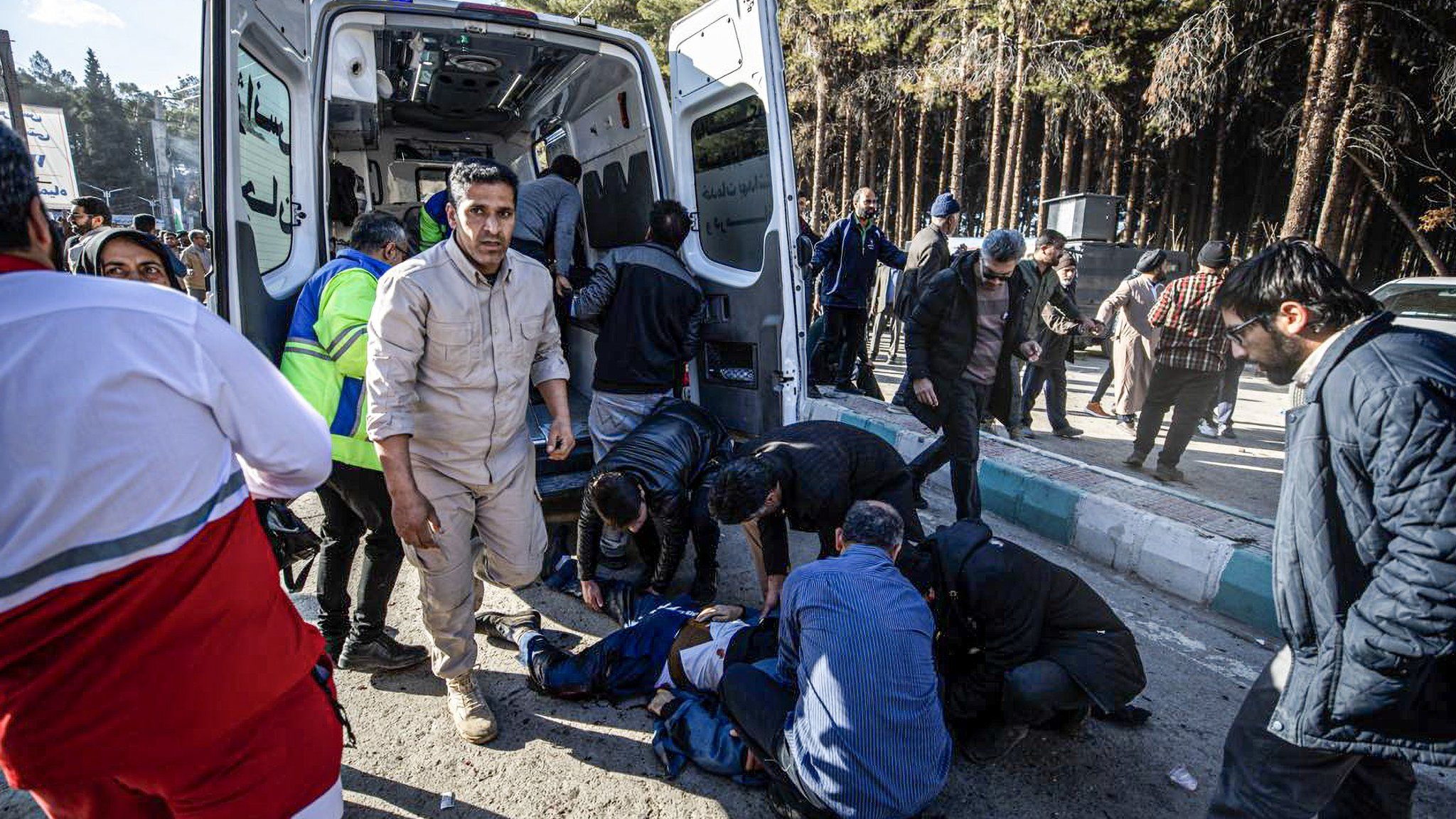 A person wounded by an explosion near Qasem Soleimani's tomb in Kerman, Iran, is treated beside an ambulance (3 January 2023)