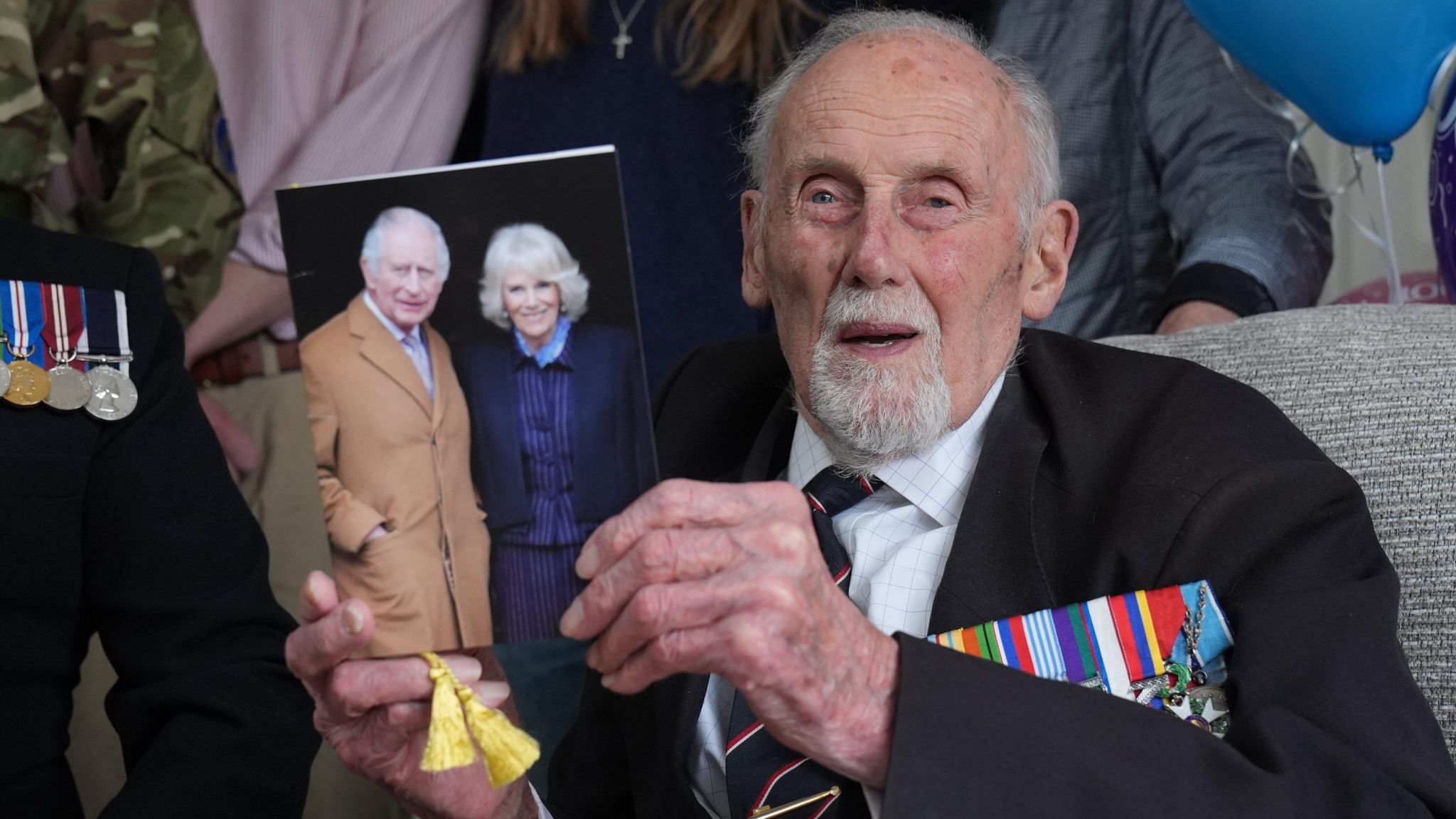John Roberts in his military uniform holding his card from the king and queen celebrating his 100th birthday