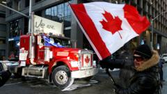 A person waves a Canadian flag in front of a truck
