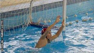 Boy defending goal playing water polo.