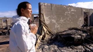 Woman looks at burnt-down home