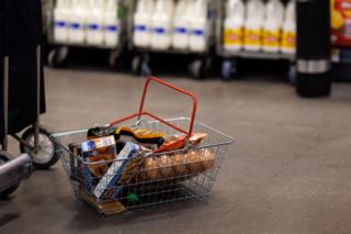shopping basket full of goods on floor of supermarket