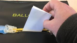 A ballot being put in a box