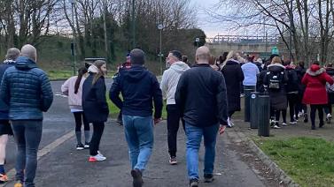 Pictured from behind, walkers crowded on a path