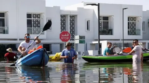 Residents move their belongings on kayaks in a flooded residential area in Dubai