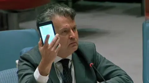 Ukrainian ambassador Sergiy Kyslytsya shows his phone