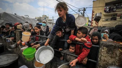 Famine looms in Gaza, Children queue to receive food at a a donation point in Rafah