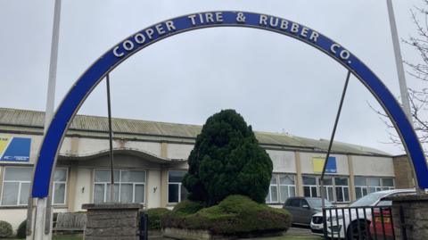 Front of the Cooper Tire factory with a blue arch over the front gate showing the company name