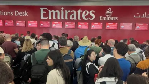 People queue at the flight connection desk the day after a storm swept across the UAE, causing flooding