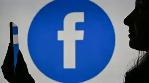 A woman in Canada looks at a phone with a Facebook logo behind her