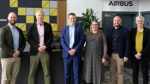 A group of people in front of an Airbus sign