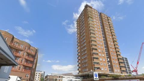 A brown tower block with a blue sky behind.
