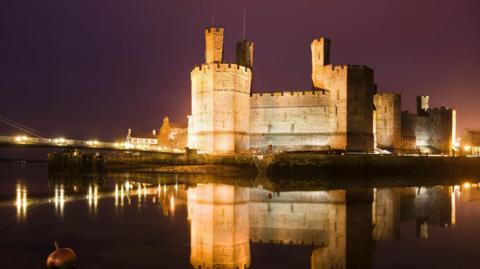 Caernarfon castle from across the river lit up at night