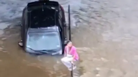 Woman abandons a vehicle after driving on a flooded parking lot in Texas
