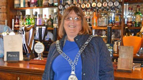 Ann Pearce in her mayoral chain standing in a pub