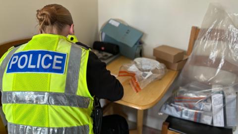 Police officer examining the recovered drugs and cash