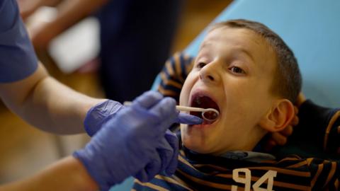 A boy has his teeth examined
