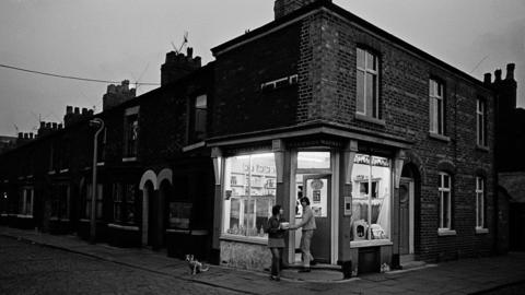 Nick Hedges, Corner shop at dusk, Salford, 1969.