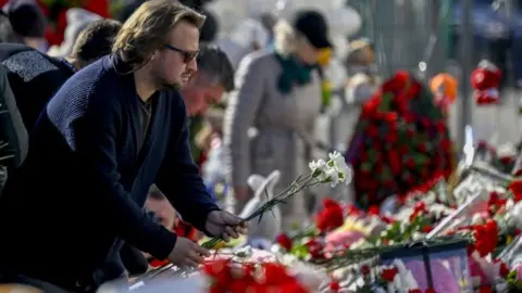 A man lays flowers outside the concert hall