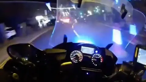 The view from the police body worn camera of an officer on a motorbike with blue lights flashing