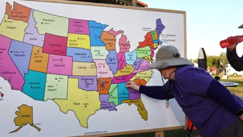 A person plots points on a map of the US