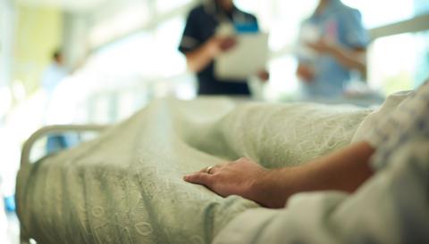 Patient lying in a bed while medical staff talk in background