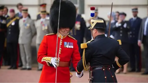 A British guard shaking hands with a French guard