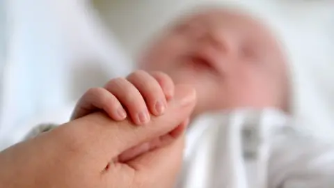 Newborn baby gripping mother's thumb