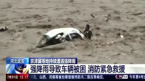 Man clinging onto the back of car in flood