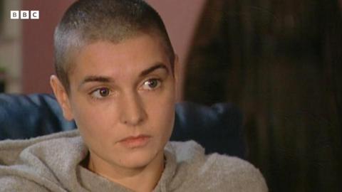 A close up of Sinéad O'Connor sitting in her home