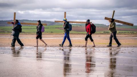 A group of walkers carrying a cross 
