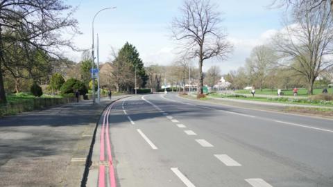 A grey tarmac road with double red lines running along the left side