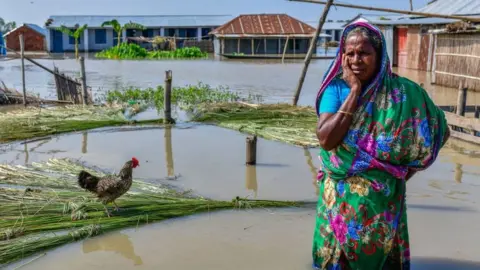 A woman stands in a flooded street in Bangladesh.